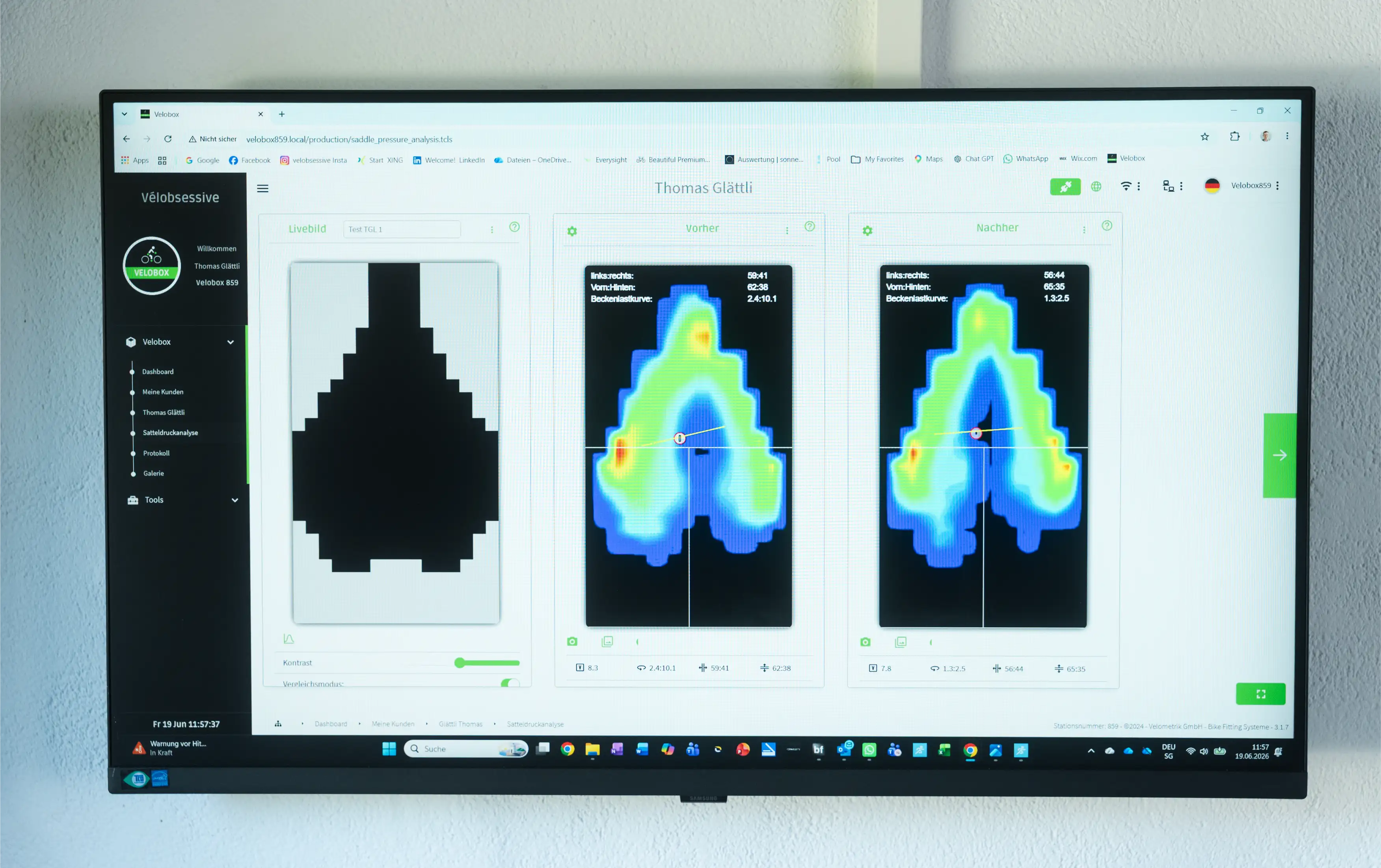 A large wall-mounted monitor displaying a software interface with three heatmaps and a black silhouette shape, photographed against a light gray wall.