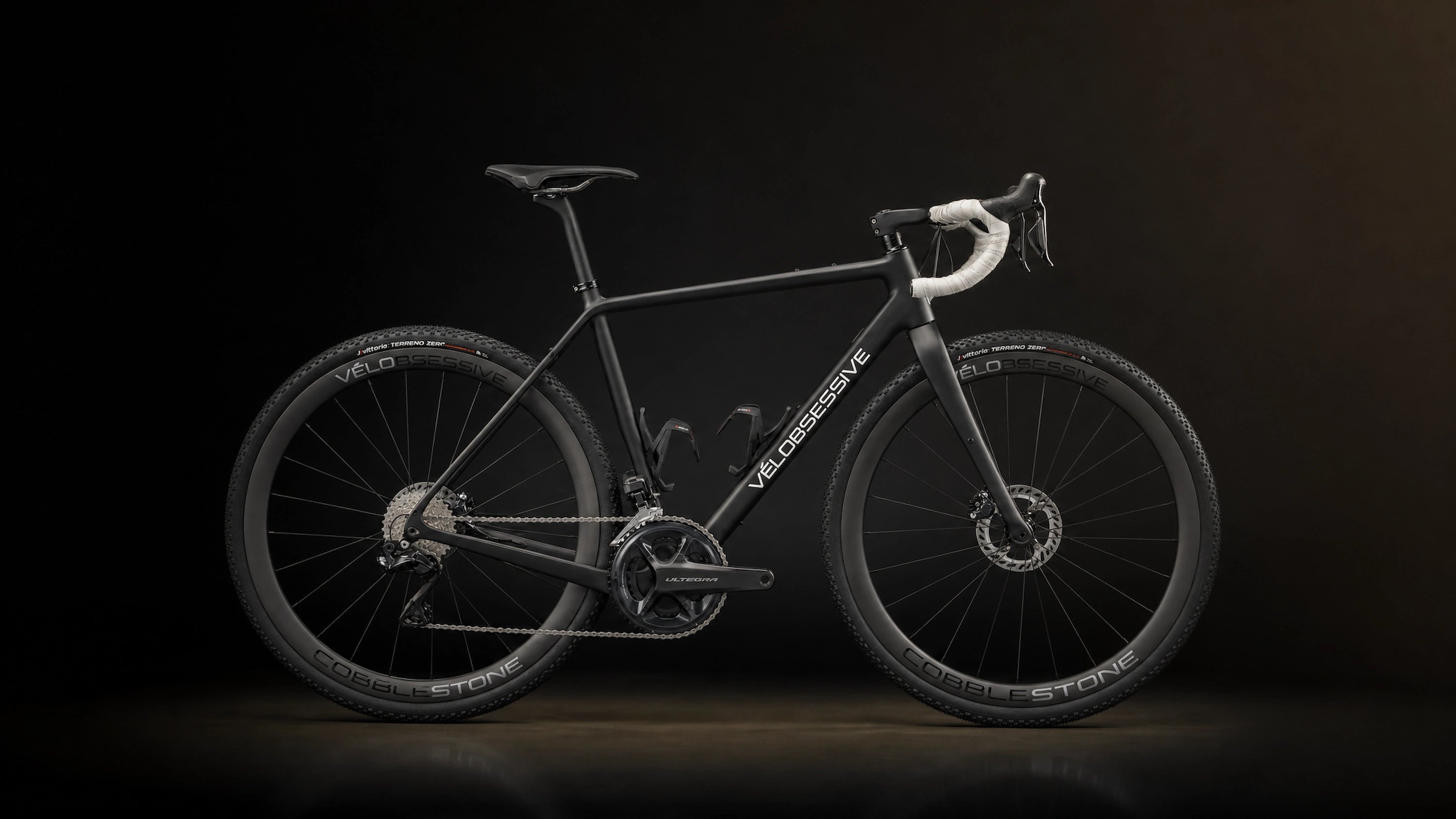 Horizontal Image of Vélobsessives Cobblestone Gravel Bike on a Black background with subtle orange gradient.